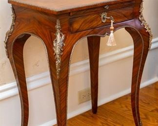 Lot #21 — Theodore Alexander Althorp Living History French Influence Style Louis XV Accent Table — 
A mahogany and ormolu mounted lamp table, the rectangular top with a moulded brass edge above a brushing slide and lockable frieze drawer, on cabriole legs with Rococo mounts terminating in sabots. The original Louis XV, circa 1760. — 
Details:
* Collection: Althorp Living History
* Style: Louis XV
* Material: Rosewood Veneer
* Dimensions: 20.5"W x 14.5"D x 27"H
