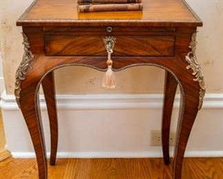 Same as Lot #21 — Theodore Alexander Althorp Living History French Influence Style Louis XV Accent Table — 
A mahogany and ormolu mounted lamp table, the rectangular top with a moulded brass edge above a brushing slide and lockable frieze drawer, on cabriole legs with Rococo mounts terminating in sabots. The original Louis XV, circa 1760. — 
Details:
* Collection: Althorp Living History
* Style: Louis XV
* Material: Rosewood Veneer
* Dimensions: 20.5"W x 14.5"D x 27"H
