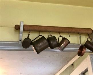 Copper and pewter mugs on vintage rolling pin