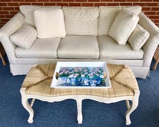 Close up picture of sofa and wood table w/ woven top