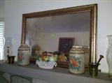 Fine antique mirror in gilt oak frame from Ashland Farm, pair of tole painted lidded canisters, Italian ceramic fruit basket, brass mortar and pestles, brass push-up candlestick in hurricane globes.