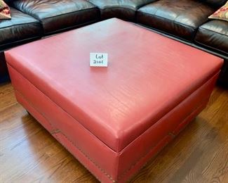 Lot 2101. $695.00 Custom Red Storage Faux Leather Ottoman. Interesting Bronze Nailhead trim on the base. Color is deep red with brown legs. Paid $2100 originally. Lots of Storage! 40" L x 40" W x 21" H
