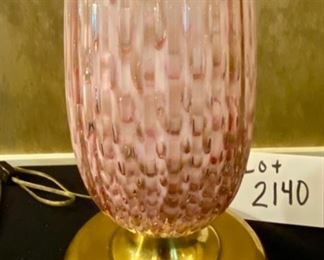 Lot 2140. Firm: $1,100.00. Handblown Murano MCM/Hollywood Regency Lamp. Ribbed Glass. Glass is pink with an underlay of cranberry and gold. Lamp tested. We didn't have a shade that paired well with this lamp. It is STUNNING. The homeowner got this lamp from her Aunt, who had it in the 50's. 35 1/2" to top of Finial x 7.5" brass base. There are two slight imperfections in the ribbing, barely noticeable. One feels as though it was part of the making process and the other one may have been a small ding that looks like it was professionally smoothed. Online a pair of these lamps have fetched $6,800 and similar versions of singleton lamps have sold for $3,500. Truly magnificent!