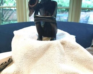 Lot 2171, $45.00. 5" African Ebony Wood carving of a man squatting wrapped in a blanket, holding an arrow quiver or drinking vessel. Signed, "MUZA" Kenya?