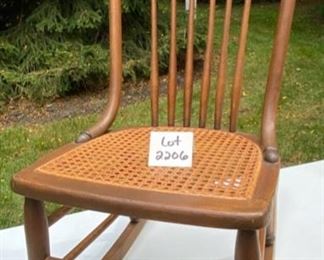 Lot 2206 $125.00 Vintage cane rocker with spindle back. 17" W x 30" D x 35" H