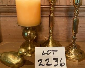Lot 2236. $18.00. Brass Lot: 2 brass candlesticks (7.5", India), 4" brass pillar holder and Candle, 1 solid brass mini duck (could be a paperweight) 4.25" long.