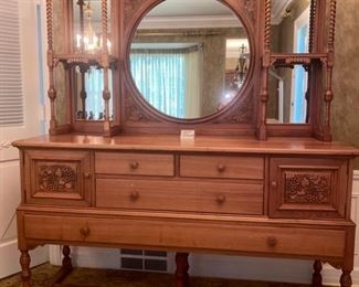 Lot 2265. $995.00. Unique Antique Buffet /Server and an open style mirror and shelving piece atop the buffet, with turned wood and interesting adornment. The two pieces coordinate, but are not an exact match, however, this was how the owners used these pieces. Selling as one lot. 4 drawers (2 w/liners for silverware) and 2 cubbies with beautiful carved front doors. "Buffet & Upper: Overall Height: 81""tall
Buffet: 66""w x 22""d x 37.25""
Upper: 43.5""h x 62""wx10.5""d. Mirror is 28.5 dia". Idea: The bottom half of this credenza could be used to hold a flat screen television, or of course as a buffet in a dining room, a foyer piece for storing gloves and hats or dog items, a bedroom as additional storage. Don't let the top piece (which is gorgeous) throw you off as to where you might use this! It's very functional in addition to beautiful.
