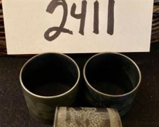 Lot 2411. $55.00. Vintage Wicker Tray with embroidery under glass (Some damage on one handle, 20"x13"), Mustard Napkins w/holder, 8 vintage place card holders (vintage flowers w/glass inserts), 12 napkin rings (signed mexican ceramics), 3 pewter or bronze napkin rings.