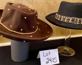 Lot 2415. $45.00. 2 ladies wool hats. 1) 100% wool felt hat, brown with gold-toned metal dots and herringbone chain. 2) 100% wool felt hat, black with brass tone ring around the hat.