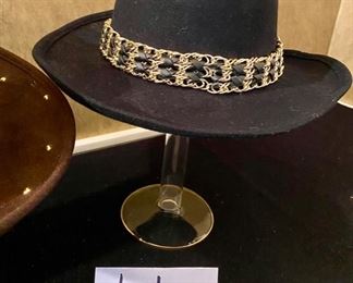 Lot 2415. $45.00. 2 ladies wool hats. 1) 100% wool felt hat, brown with gold-toned metal dots and herringbone chain. 2) 100% wool felt hat, black with brass tone ring around the hat.