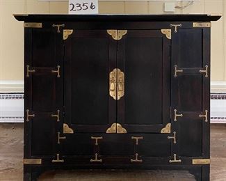 Lot 2356. $175.00. Small 2 door Asian inspired side table/cabinet. Black and Brass. Very very solidly made and heavy! The interior is open, no shelves, great extra storage. Cool brass details. 26"w x 16" d x 22" tall