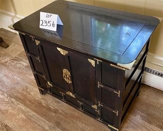 Lot 2356. $175.00. Small 2 door Asian inspired side table/cabinet. Black and Brass. Very very solidly made and heavy! The interior is open, no shelves, great extra storage. Cool brass details. 26"w x 16" d x 22" tall