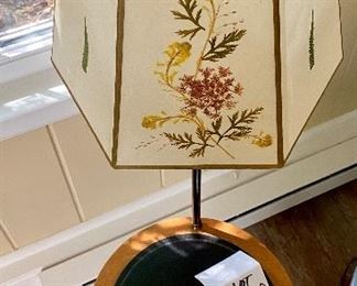 Lot 2360. $125.00. Swivel Table Floor Lamp with semitransparent pressed botanical shade (there are different flowers on 3 panes). Vintage. The tabletop is leather (I believe) and the base is brass. Well-made. The wood border on the table could use a little Old English, which should clean it up nicely. 15" dia table, 50" tall