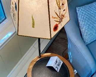 Lot 2360. $125.00. Swivel Table Floor Lamp with semitransparent pressed botanical shade (there are different flowers on 3 panes). Vintage. The tabletop is leather (I believe) and the base is brass. Well-made. The wood border on the table could use a little Old English, which should clean it up nicely. 15" dia table, 50" tall