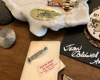 Lot 2446. $48.00. 2 glass paperweights and Jewelry Lot: 4 pins/broaches- "House Pins by Lucinda (ME), Japanese Coat w/hummingbird, Jean Coldwell Arnold watch face, "Wearable Art by Rosemary from Pana, IL". 1 cloisonne belt buckle/tie gatherer, 3 clip earrings, 2 pierced.
