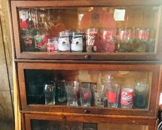 collectible coca cola glasses, mugs, etc... in 4 section barrister cabinet 