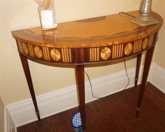 Refined half-round pier table is richly figured mahogany with satinwood inlay. Demilune top has satinwood scallop border and radiant fan inlay. Square tapered legs feature inlaid panels
