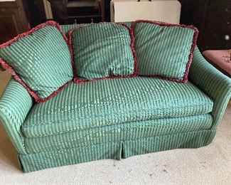 Green striped love seat with matching throw pillows with red ruffle trim
