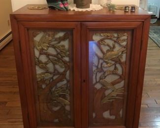 Teak two door cabinet with glass over carved doors. 