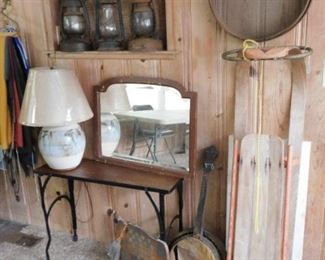 Old toboggan, railroad lanterns, wood and iron narrow table on casters, antique sieve, dead banjo.