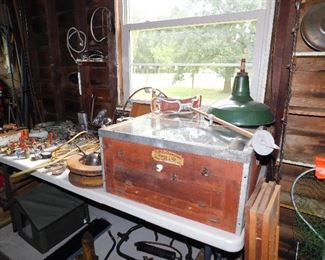 Table full of metal artist objects and an antique chick incubator