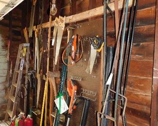 Shepherd's hooks, huge old iron clamps, saws, Homelite blower/vac, Black & Decker trimmer, axes, jumper cables, shovels, grease guns, fire extinguishers.
