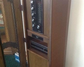 Living Room:  A side  view of the MAGNAVOX retro stereo cabinet shows one of the speakers.  Its measurements are 15" wide x 16" deep x 43" tall.