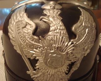 Near Cashier:  The Prussian guard helmet's emblem is a raised wing eagle with the embossed words:  "Mit Gott Fur Koenig und Vaterland" (translation: "With God For King and Fatherland").  A silver guard star is attached to the eagle's breast.  The eagle holds a sword in one talon  and a torch in the other.  (Note:  This is NOT a WWII Nazi helmet; they typically depicted an eagle with a swastika in its talons.) 