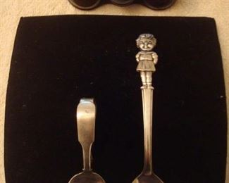 SMALLS Area-CASE:  Vintage  MERMOD-JACCARD binoculars are above a sterling baby spoon and a collectible silver-plate CAMPBELL'S SOUP GIRL spoon.