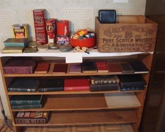 Lower Level:  Vintage tins; a canister of old match books; corn cob pipes; a wooden box filled with metal boxes; and books; are all priced for you!
