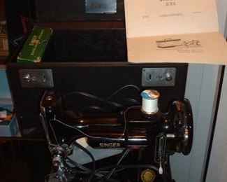 Lower Level:  A vintage SINGER Featherweight 221 sewing machine has its own case and instructions, (AL411608). 