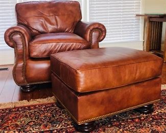 Overstuffed Hancock and Moore  leather arm chair and ottoman with brass nailhead trim.