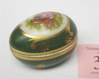 A porcelain egg trinket box  marked Limoges France.  1.75" long.  Transfer image of an 18th couple on the lid.  