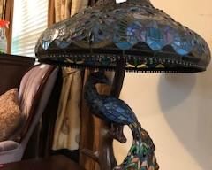 Tiffany table lamp with attached Tiffany peacock (there is a separate small bulb on base that illuminates the peacock). Iron tree design base. 