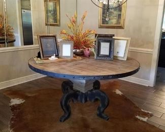 Round reclaimed wood dining table with iron band on cowhide rug