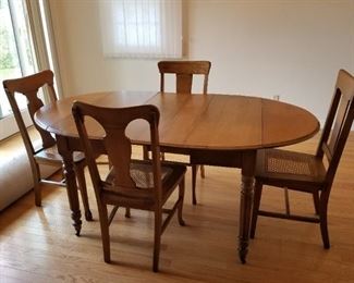 OAK ROUND TABLE WITH 2 LEAVES TO MAKE A LARGE OVAL TABLE -- 4 OAK CHAIRS WITH CANE SEATS SOLD SEPARATELY