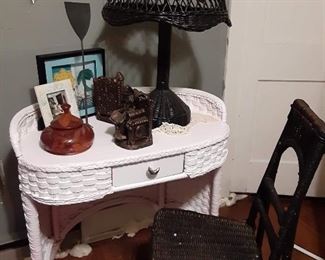 Wicker end table with drawer. Wicker chair. Wicker tabletop lamp. Miscellaneous knick knacks and decorations. Wood calendar on wall.