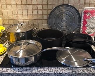 Cookware: yellow enamel colander & crumpet pan, Kirkland pans, cast iron Dutch oven & skillets, induction converter discs