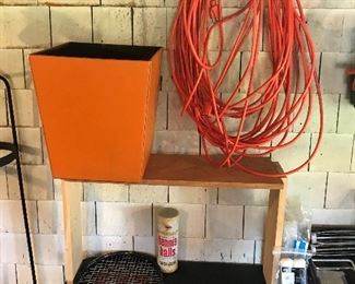 Extension cord, tennis racket and orange storage bin