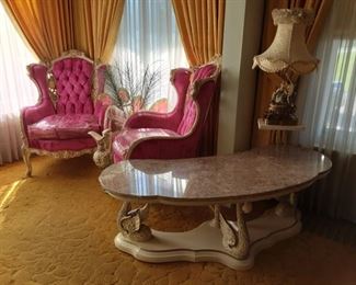 Overall view of pink Italian chairs, a Capodimonte table lamp, kidney shaped marble coffee table on carved wood base of swans.