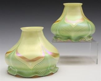 A Pair of Early 20th century Steuben Calcite & Aurene Glass Shades.  Each having a flared rim that tapers into a bell form body with a ruffled base, decorated with a pulled feather motif in Green and Gold.  No apparent markings, shape number 2290.  Each with minor surface scratches.  5 1/4 x 4 1/4" high, fitter is 2 1/4". 