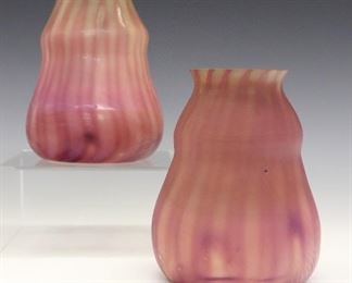 A Pair of Early 20th century Art Glass Shades.  Each with alternating clear to Purple linear patterns with faint pulled feather motif at the bases.  One is etched "L.C.T. S3583" and the other "L.C.T. S3592" at the fitter rims.  Some surface scratches and chips to the fitter rims.  4 1/4 x 5 1/2" high, fitters are 2 3/8". 