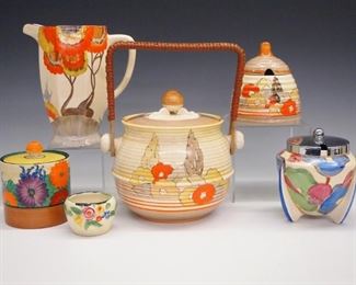 A collection of six pieces of Clarice Cliff earthenware. Includes Bizarre ware, jug, biscuit barrel, two jam jars, a honey pot and small floral pot.  Printed marks.  Some wear to the decoration, the "Gay Day" jam has a production flaw to the rim.  Up to 6" high.  ESTIMATE $600-800