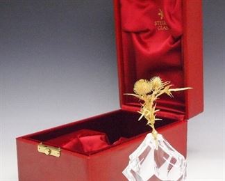 A Steuben Crystal "Thistle Rock" Sculpture.  Consisting of a vermeil cluster of thistles within a clear crystal rock form base; model 1011, designed by James Houston in 1967.  Signed "Steuben" at the underside, includes original presentation case and box.  Light wear overall, both boxes show some wear.  4 x 3 1/2 x 7" high.  ESTIMATE $600-1,000