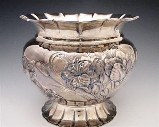 A 20th century Italian Sterling Silver jardiniere by Fratelli Cacchione, Milan.  Flared piecrust rim on a bulbous body with flowers and cattails in deep relief on a circular petaled base.  Stamped marks at underside include "F C, Sterling....925" .  46.93 troy ozs.  Minor wear.  8" high.  ESTIMATE $2,000-3,000
