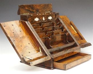 A 19th century English Victorian Period Burl Walnut stationary box.  Two sloped doors open to reveal an interior fitted with stationary, pen and inkwell compartments below a roller calendar with hinged cover, with a locking drawer at the base.  Original finish with minor wear.  13 x 10 1/2 x 13" high.  ESTIMATE $200-300