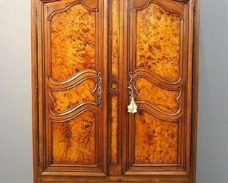A 19th century Country French Louis XV style provincial armoire from Bresse in Northeastern France.  Cherry and Walnut construction with solid Burl Ash decorative panels.  Features a molded lift-off cornice over a shaped three panel frieze and two long doors with shaped tops, each having three shaped, molded panels, full length forged steel hinges and shaped escutcheons over a single drawer with paneled facade, a shaped apron and short cabriole legs. Interior fitted with removeable shelves and drawers.  Older restored finish with minor wear and some repair.  63 x 28 x 95" high overall.  ESTIMATE $2,000-4,000