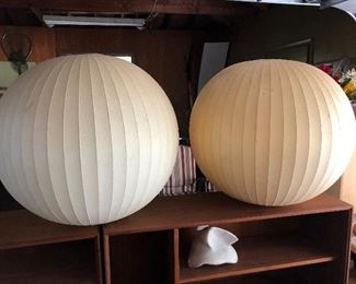 Two large mid-century globe shades sitting atop a pair of mid-century chests/shelves.