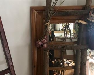 A really big pine mirror and a rustic ladder.  To the left is a crimson chinese antique ladder