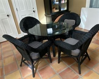 Lot 3156. $395.00. Vintage Black Wicker Round Table With Glass Top and 4 Chairs with cushions. Has hole for an umbrella, however, this was described to us as an indoor wicker set.  Still, an umbrella would look cute even indoors!    Cushions are Polkadot and in good shape.  